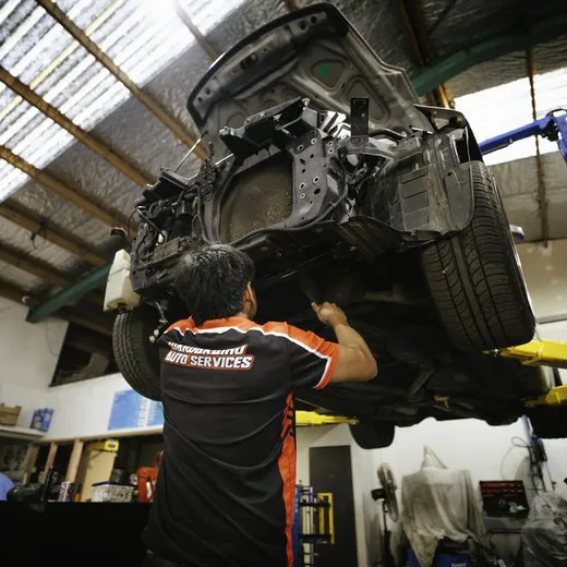 Technician inspecting a vehicle raised on a workshop hoist