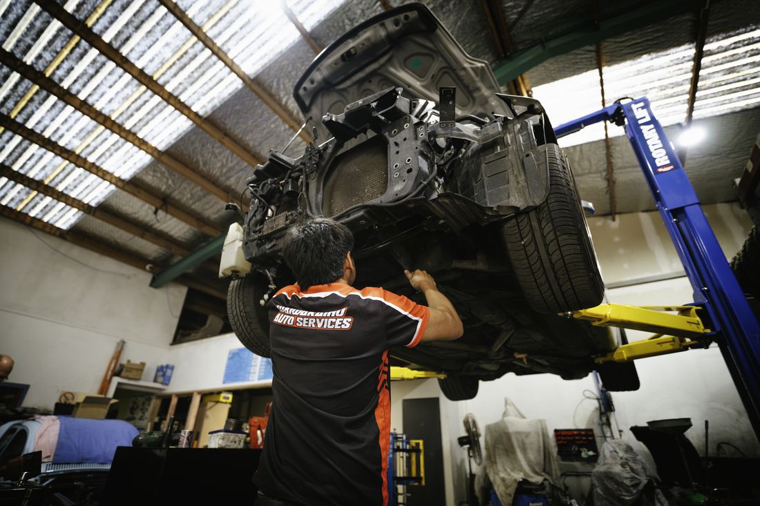 Technician working beneath a vehicle on a workshop hoist